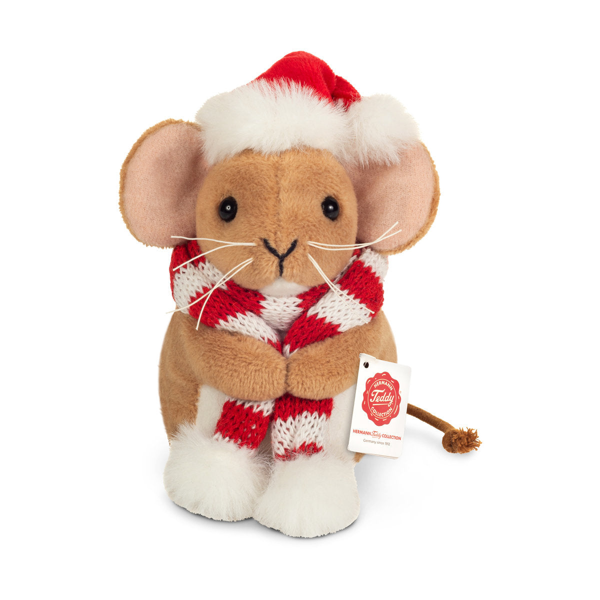 Det här är en julmus från Teddy-Hermann. Sittande mus med kort, tät beige päls med svag glans och kort, fluffig vit päls på magens framsida och fötternas ovansida. Nosen är beige med långa vita morrhår, öronens insida ljusrosa, ögonen svarta och runda och nosspetsen svart och V-formad. Svansen är tunn och brun med en knut i änden. På huvudet en röd tomteluva med vit fluffig kant, runt halsen en rödvitrandig stickad halsduk med vita fluffiga pomponger. Milt, nöjt uttryck.