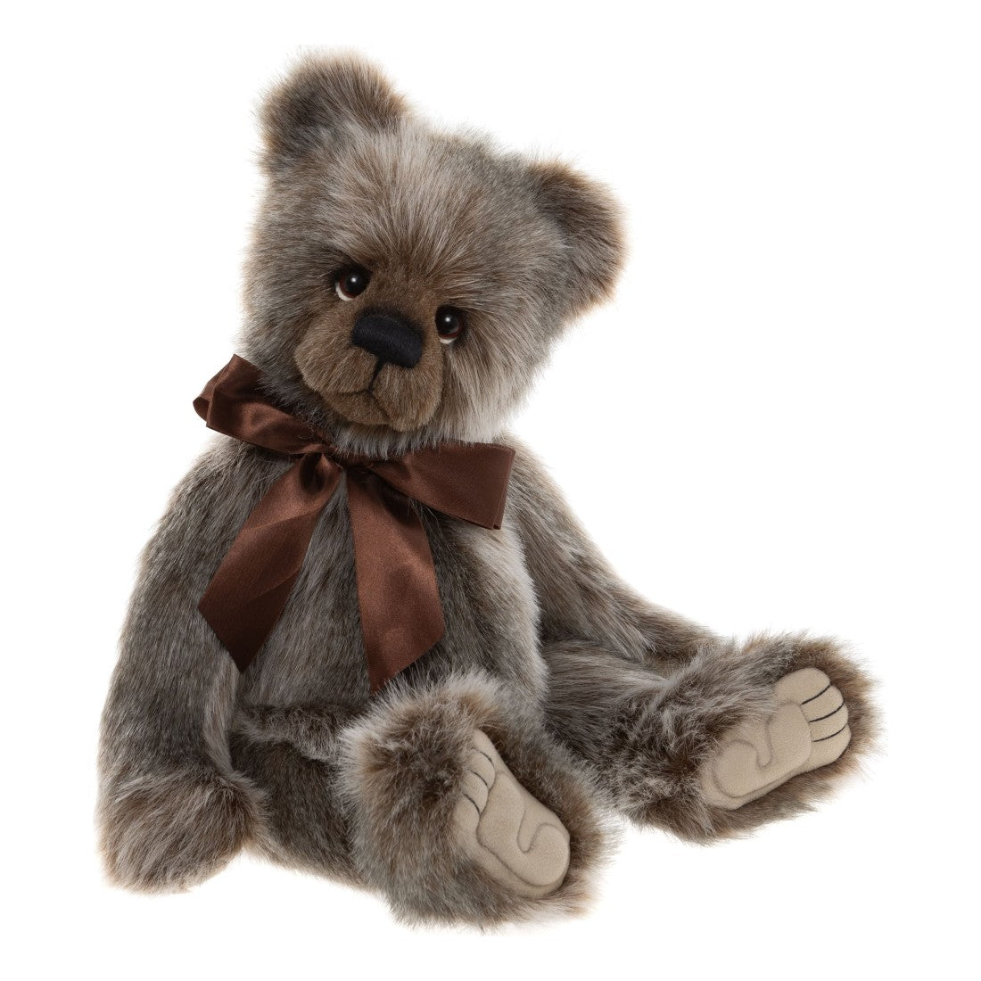 Det här är Ollie, en nalle från Charlie Bears. Hen sitter och har lång, rak päls i grått med tydliga bruna toner, små vita partier och lätt glans. Nosen är brun, öronens insida grå med bruna kanter, magen och yttertassarna gråbruna och trampdynorna beige. Ögonen är mörkbruna och blanka med vitmålade halvmånar under, nosknappen svart och rektangulärt oval med broderad mun. En stor rostbrun satinrosett sitter knuten om halsen, och minen är mild och vemodig.
