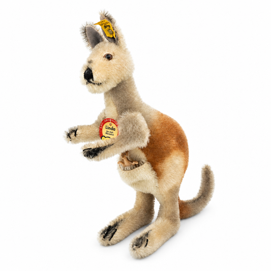 Det här är Linda, en känguru från Steiff. Hon är handgjord i mohair, står upprätt på bakbenen och känns fast. Pälsen är beige på huvud, bröst, ben och pung och varmbrun på rygg och bakdel, kort och lite rufsig med svag glans. Svansen är lite grå, öronens insida mörkare grå och runt mun och nos finns svarta markeringar, liksom på tasspetsar och klor. Nospartiet är beige, ögonen bruna, nosen svart och rund. I pungen sitter en kängurunge i plast och uttrycket verkar vaket.